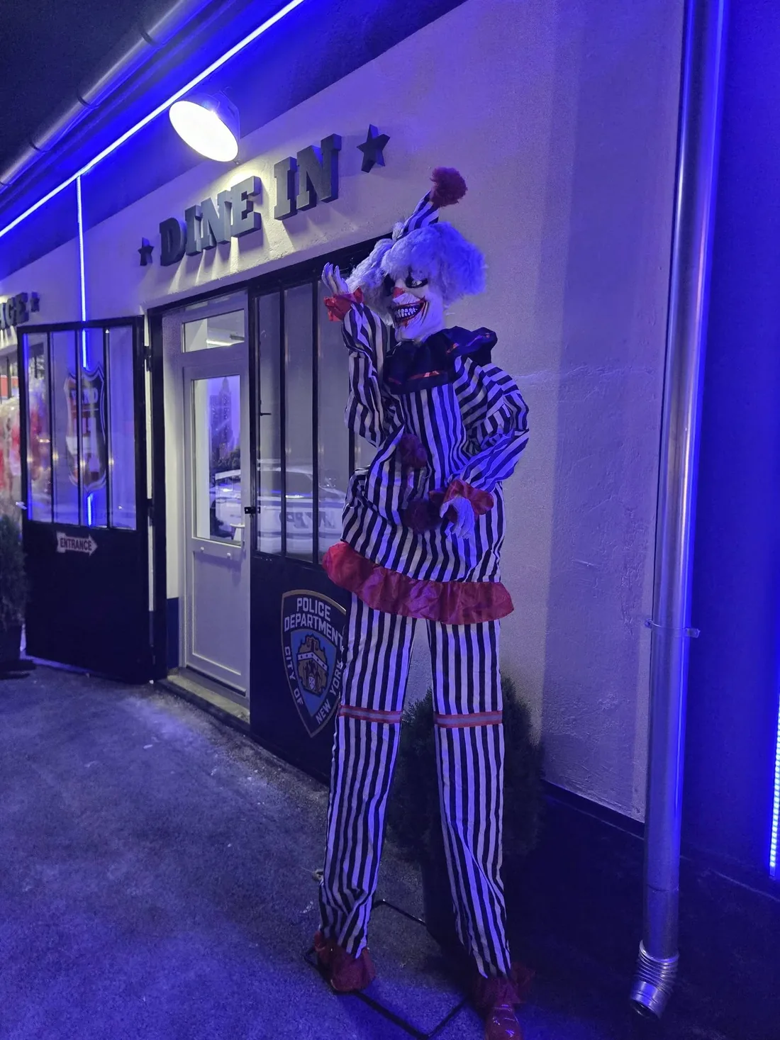 Bohócfigura a Dine in bejáratnál, kék neonfényben